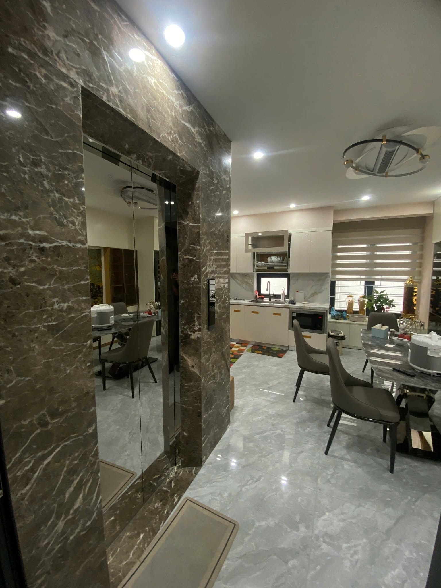Cửa thang máy ốp đá cạnh không gian bếp và bàn ăn của gia đình
