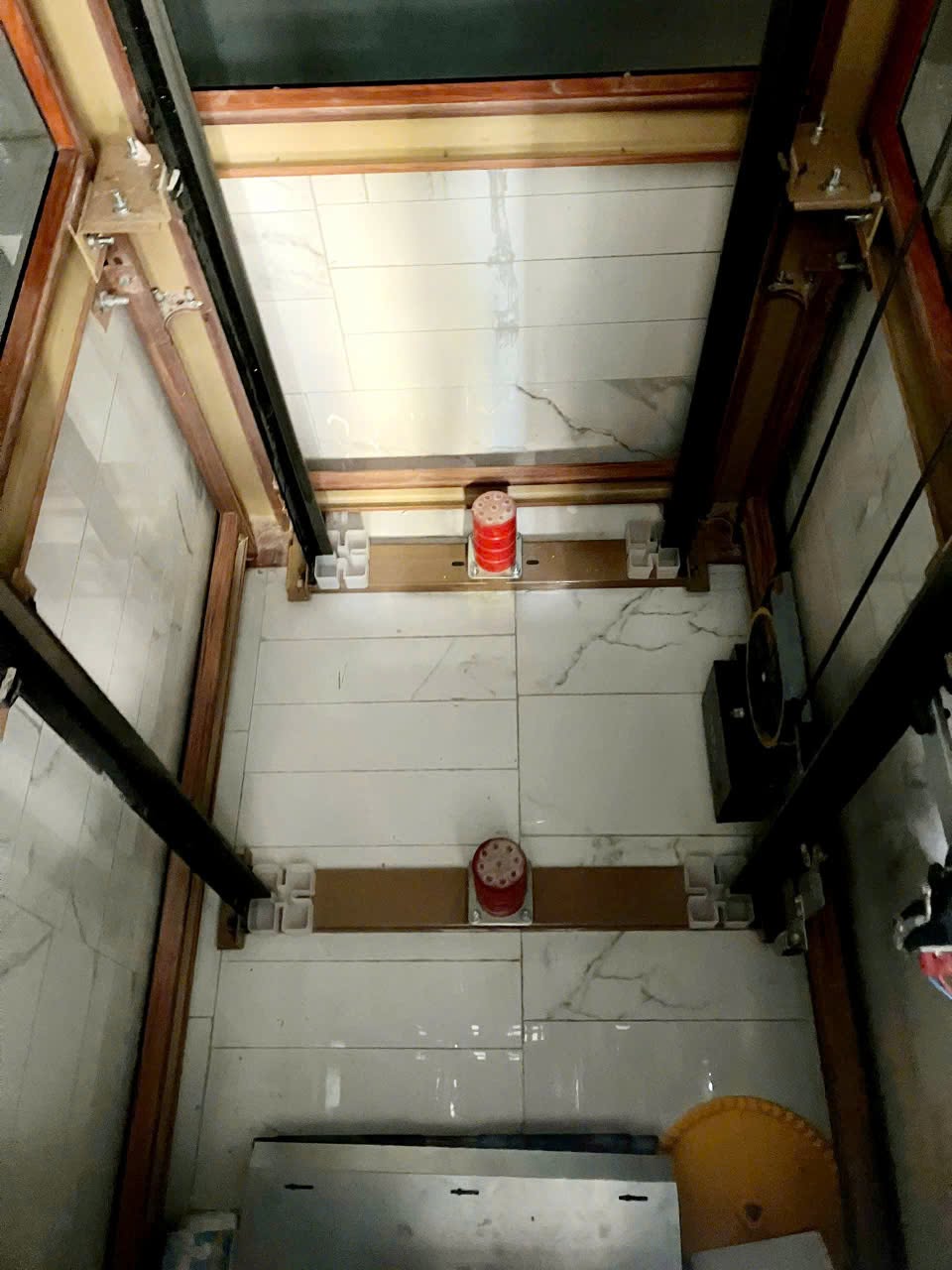 Bề mặt hố pit lát gạch, cùng ray dẫn hướng và các bộ phận thiết bị thang máy